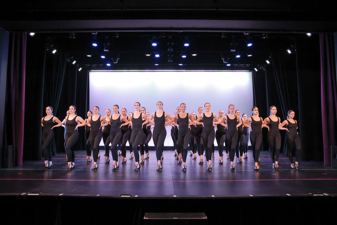 Full company in synchronized formation on stage
